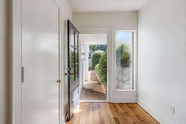 a view of a hallway with wooden floor and a living room filled with closet