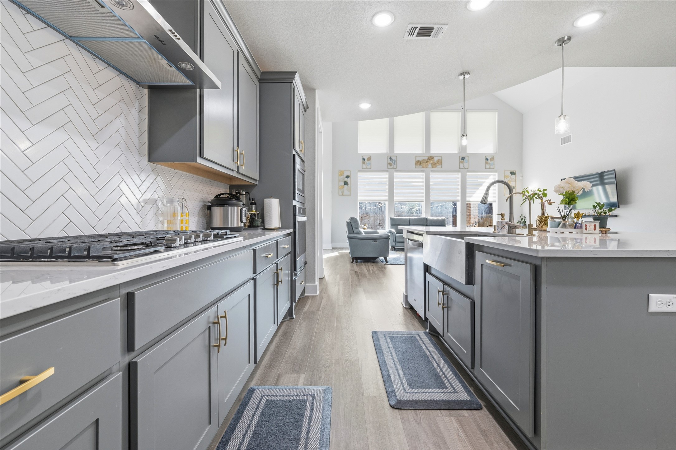 105 Autumn Oak Way Georgetown, TX 78628 - Photo 18 of 40 Kitchen featuring gray shaker-style cabinetry, a white herringbone tile backsplash, white countertops, wood-finish flooring, and an apron-front sink