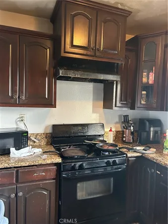 a kitchen with granite countertop a stove top oven sink and cabinets