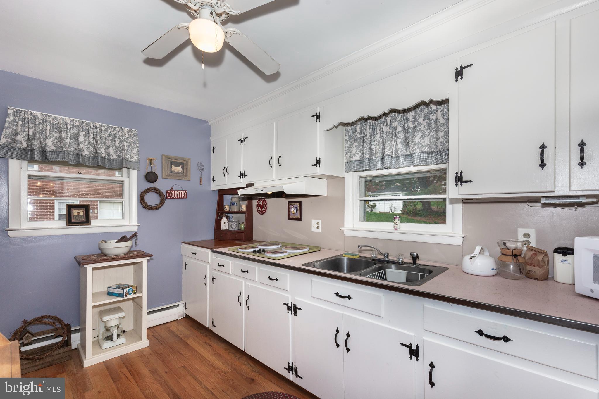 804 William Avenue Westminster, MD 21157 - Photo 6 of 20 a kitchen with stainless steel appliances a sink dishwasher stove and white cabinets with wooden floor