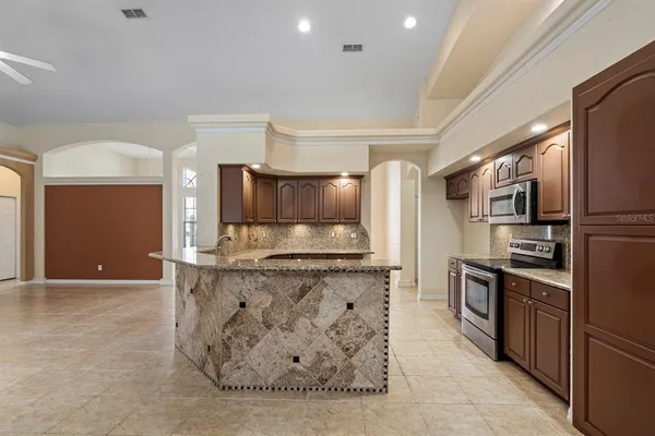 a kitchen with stainless steel appliances kitchen island granite countertop a refrigerator a stove and a sink