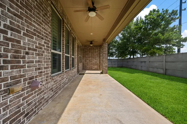 a view of a backyard with brick wall and potted plants