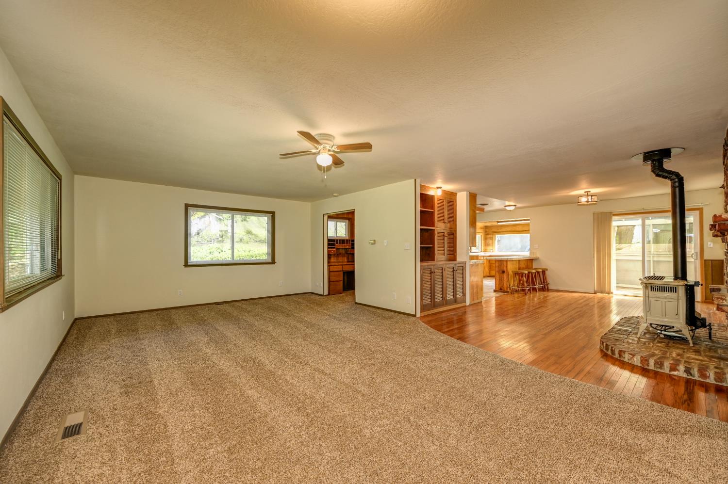 4541 Meadowbrook Road Garden Valley, CA 95633 - Photo 21 of 71 unfurnished living room with a wood stove, light carpet, and ceiling fan