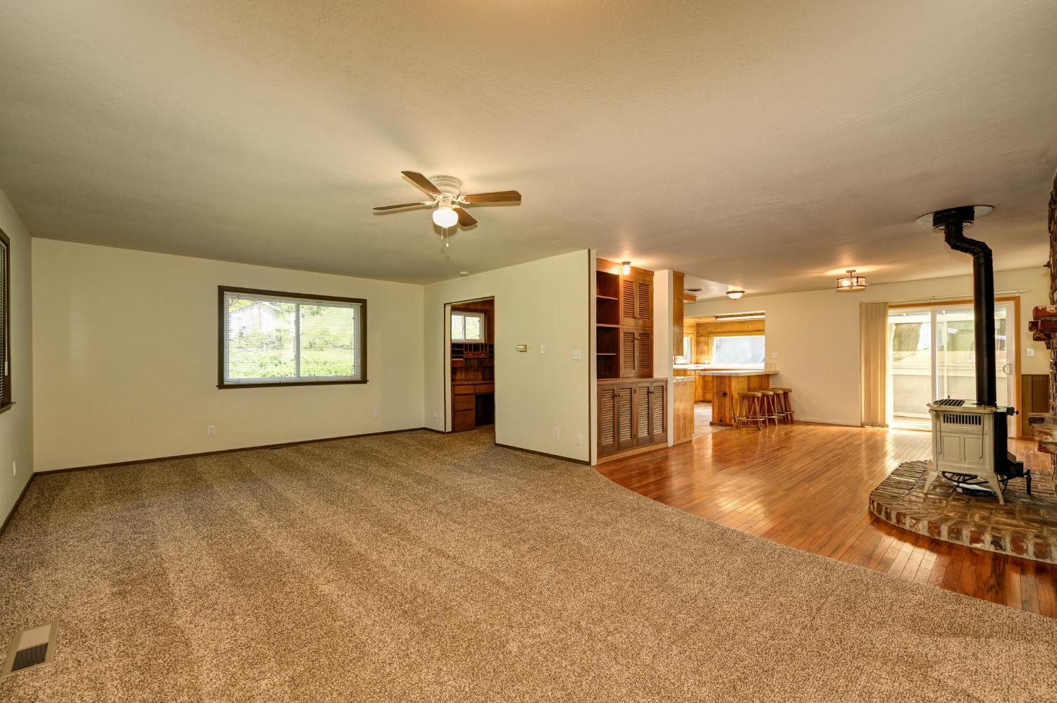 4541 Meadowbrook Road Garden Valley, CA 95633 - Photo 22 of 71 unfurnished living room with carpet flooring, a wood stove, and a ceiling fan