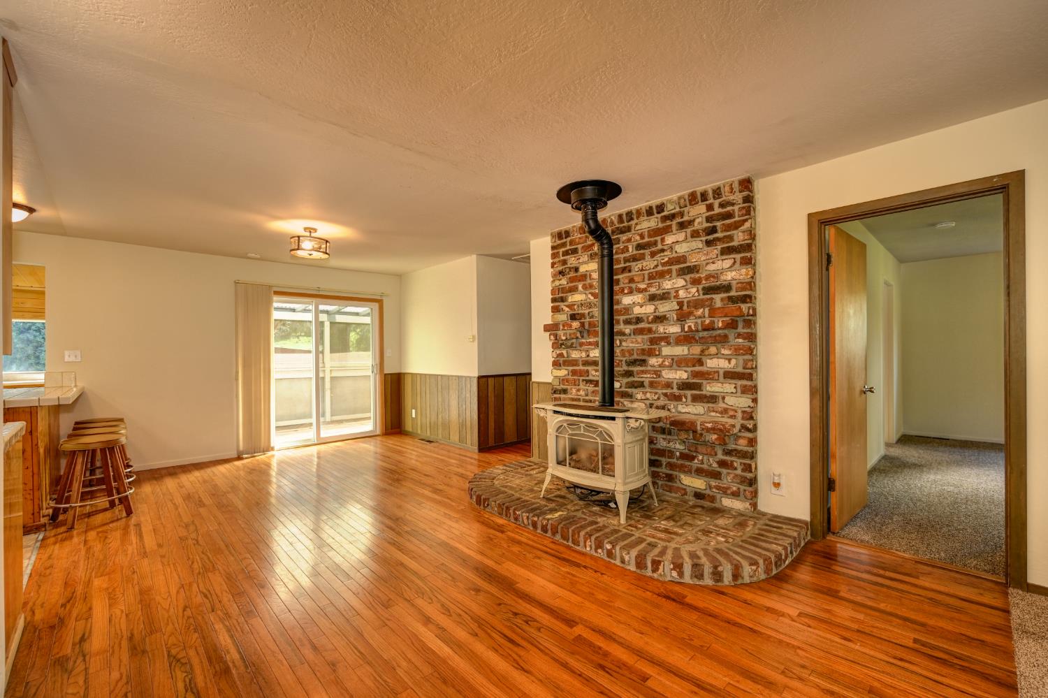 4541 Meadowbrook Road Garden Valley, CA 95633 - Photo 27 of 71 unfurnished living room featuring wood-type flooring, a wood stove, and a textured ceiling