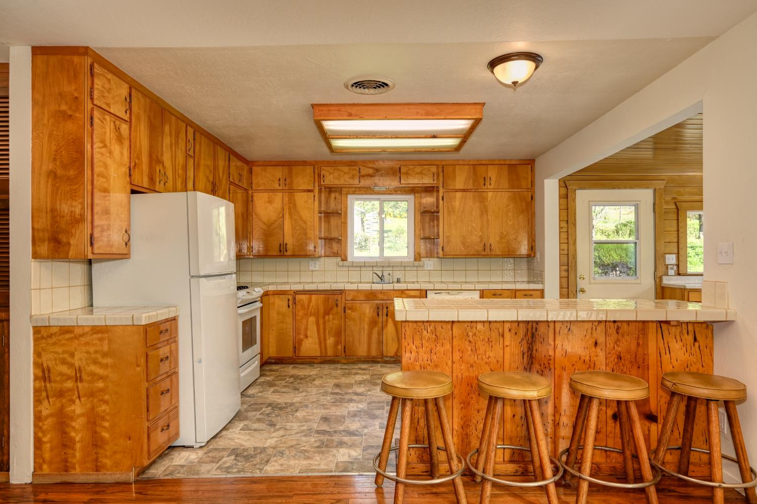 4541 Meadowbrook Road Garden Valley, CA 95633 - Photo 30 of 71 kitchen featuring tile counters, white appliances, wood finish cabinets, and backsplash