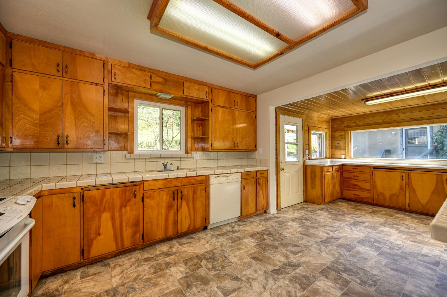 4541 Meadowbrook Road Garden Valley, CA 95633 - Photo 32 of 71 kitchen featuring stone finish floors, wood finish cabinetry, tile countertops, white appliances, and open shelves