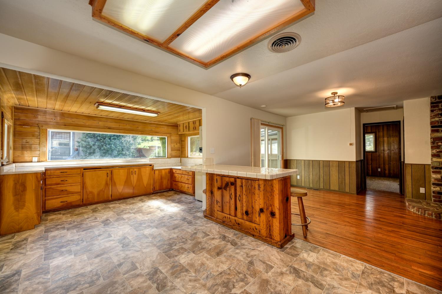 4541 Meadowbrook Road Garden Valley, CA 95633 - Photo 33 of 71 kitchen with wooden walls, wainscoting, stone finish flooring, a peninsula, and tile countertops