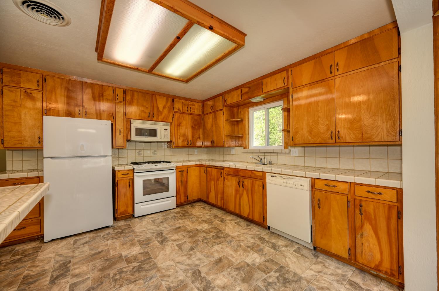 4541 Meadowbrook Road Garden Valley, CA 95633 - Photo 34 of 71 kitchen with tile counters, stone finish flooring, white appliances, and backsplash