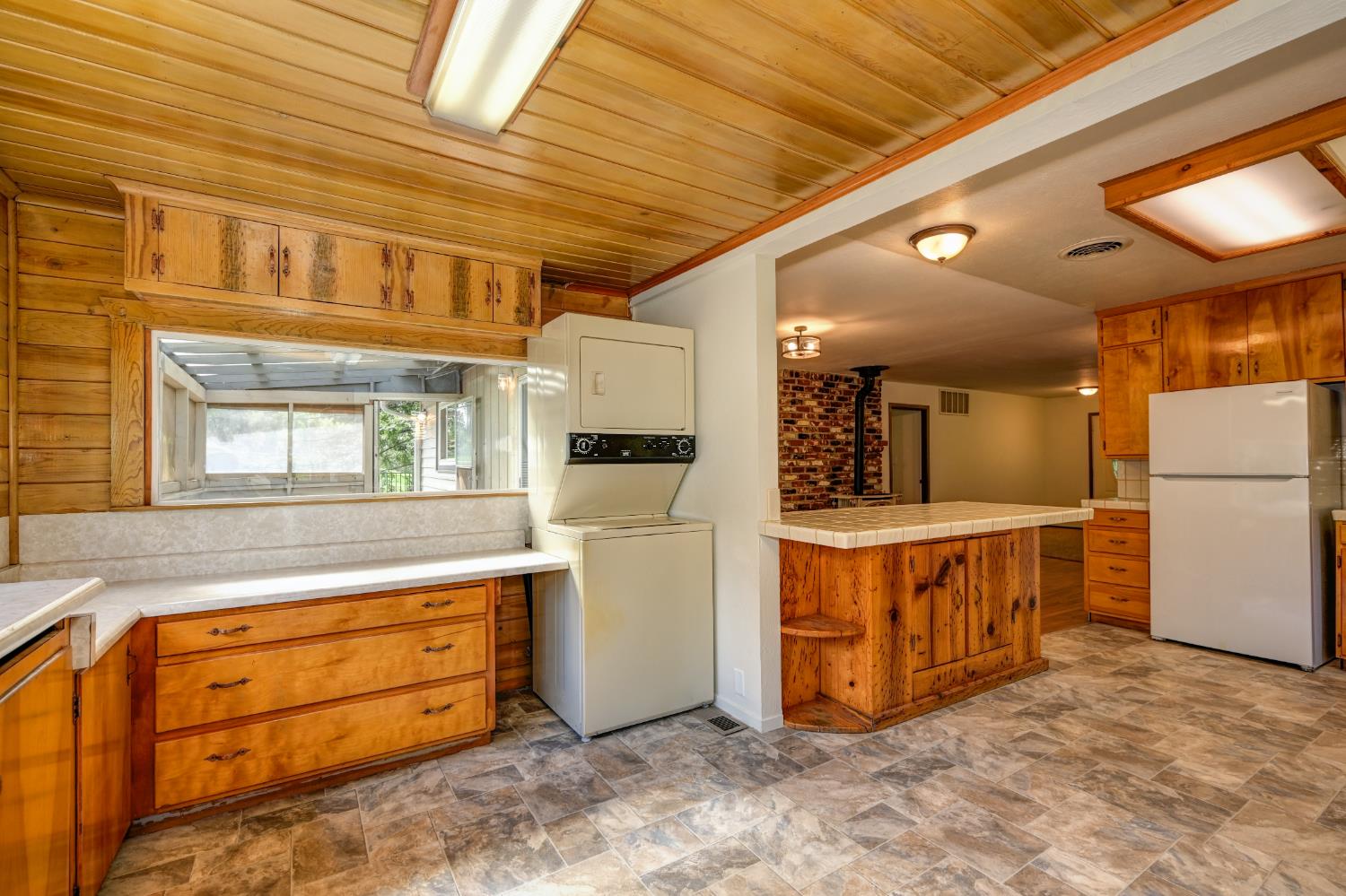 4541 Meadowbrook Road Garden Valley, CA 95633 - Photo 37 of 71 kitchen featuring stone finish floors, freestanding refrigerator, wood ceiling, wood finish cabinetry, and ornamental molding