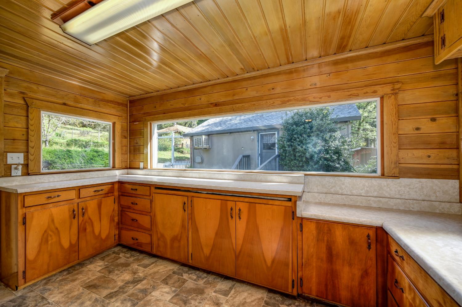 4541 Meadowbrook Road Garden Valley, CA 95633 - Photo 39 of 71 kitchen featuring light countertops, stone finish flooring, wood ceiling, wood finish cabinetry, and wooden walls