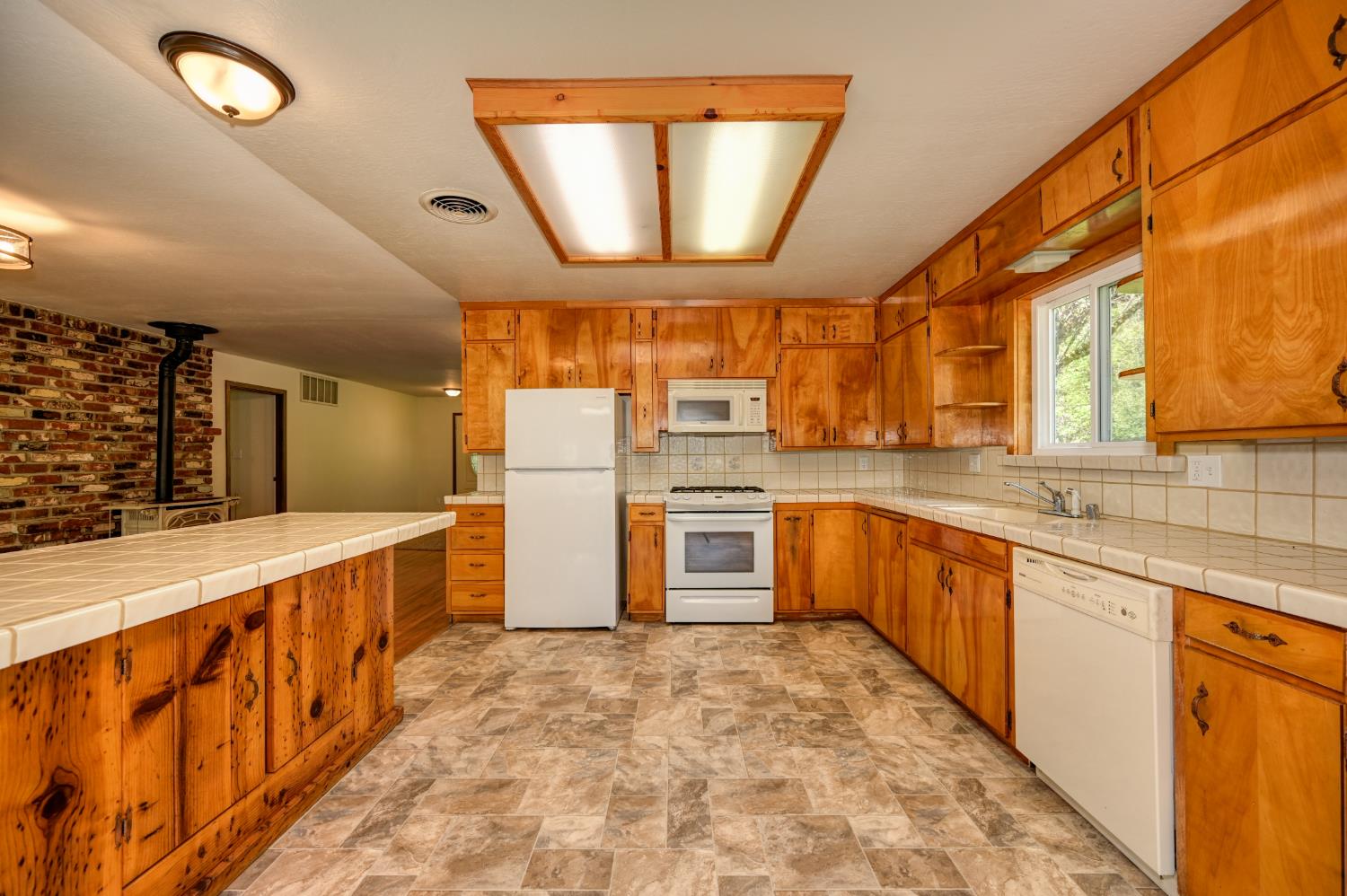 4541 Meadowbrook Road Garden Valley, CA 95633 - Photo 40 of 71 kitchen featuring tile countertops, stone finish flooring, wood finish cabinetry, white appliances, and open shelves