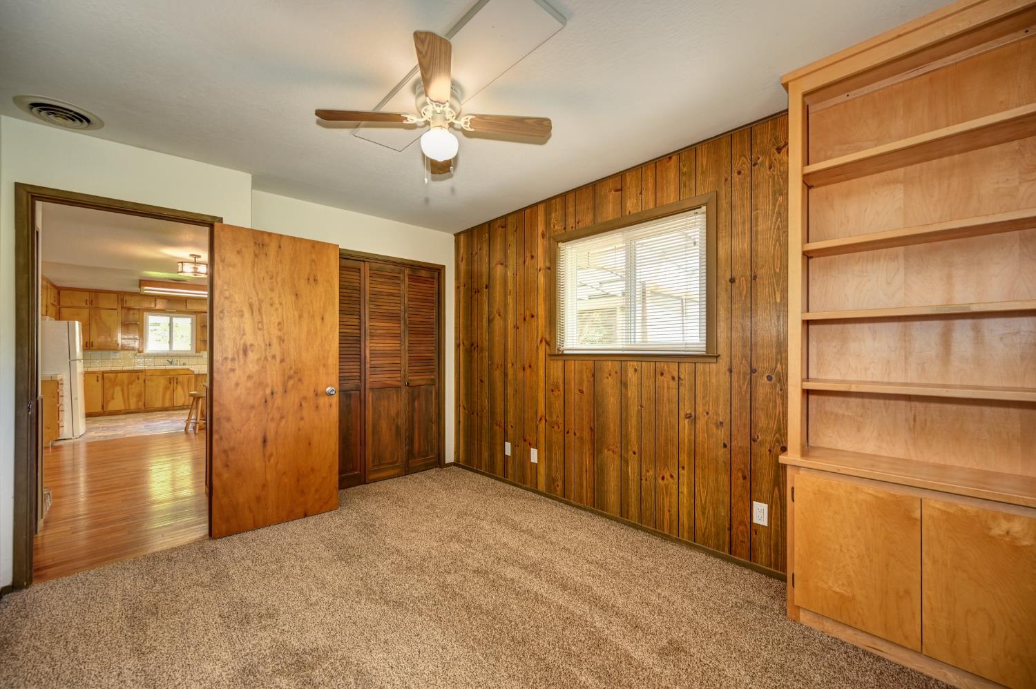 4541 Meadowbrook Road Garden Valley, CA 95633 - Photo 42 of 71 unfurnished bedroom with a closet, light colored carpet, wooden walls, freestanding refrigerator, and ceiling fan