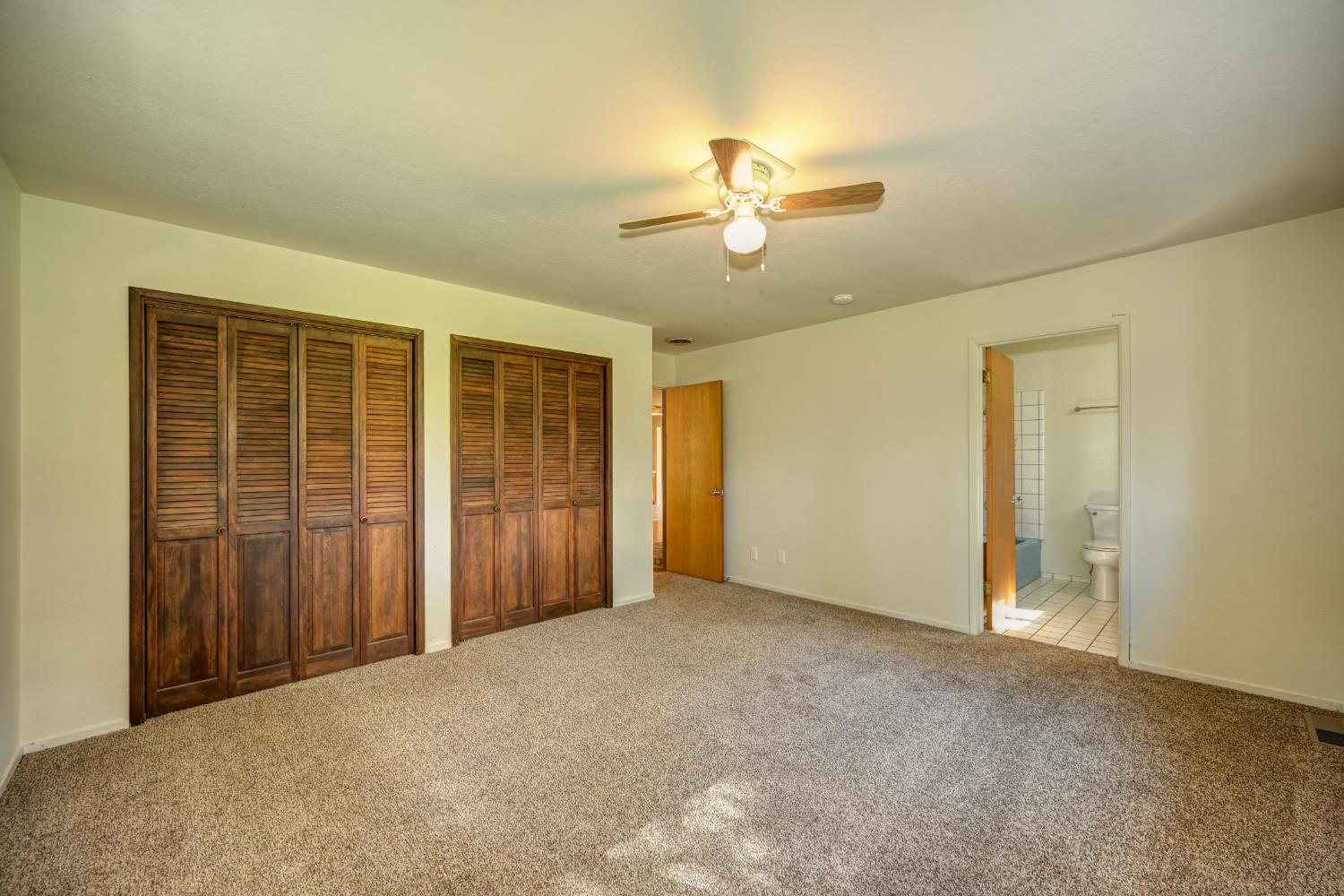 4541 Meadowbrook Road Garden Valley, CA 95633 - Photo 49 of 71 unfurnished bedroom with multiple closets, carpet flooring, a ceiling fan, and ensuite bathroom