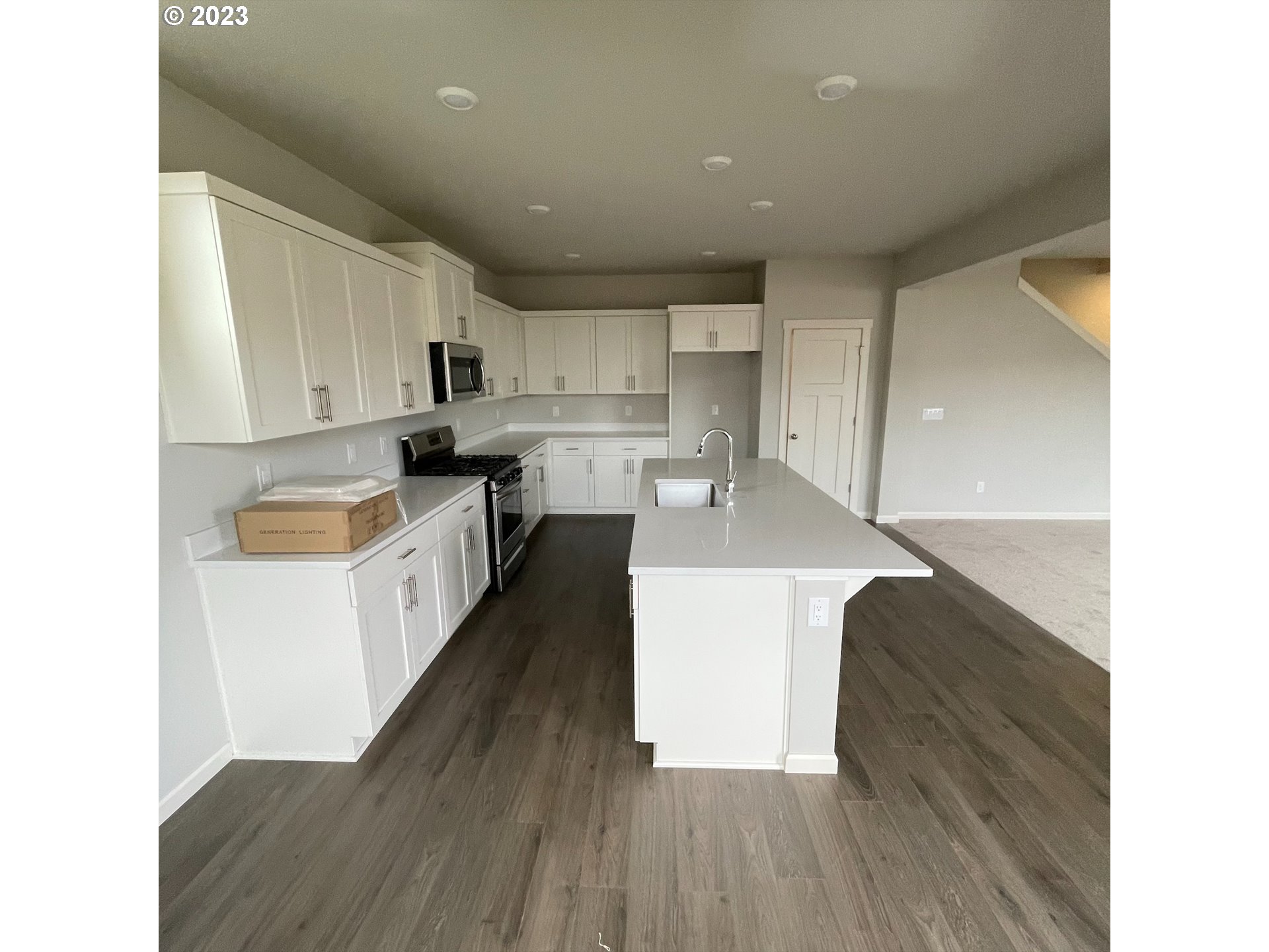 2083 Southeast Pheasant Avenue Gresham, OR 97080 - Photo 23 of 30 a kitchen with kitchen island a stove a sink a refrigerator and white cabinets with wooden floor