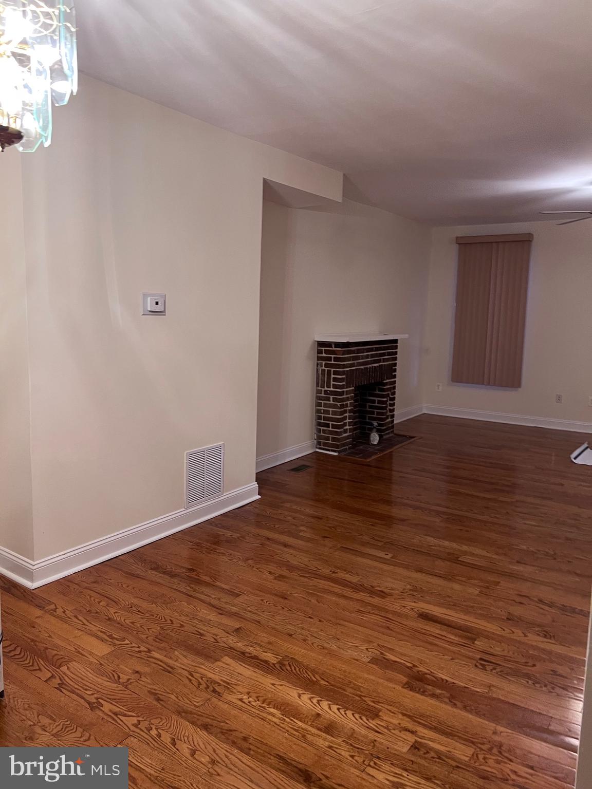 1634 Chilton Street Baltimore, MD 21218 - Photo 3 of 18 a view of an empty room with wooden floor and a fireplace