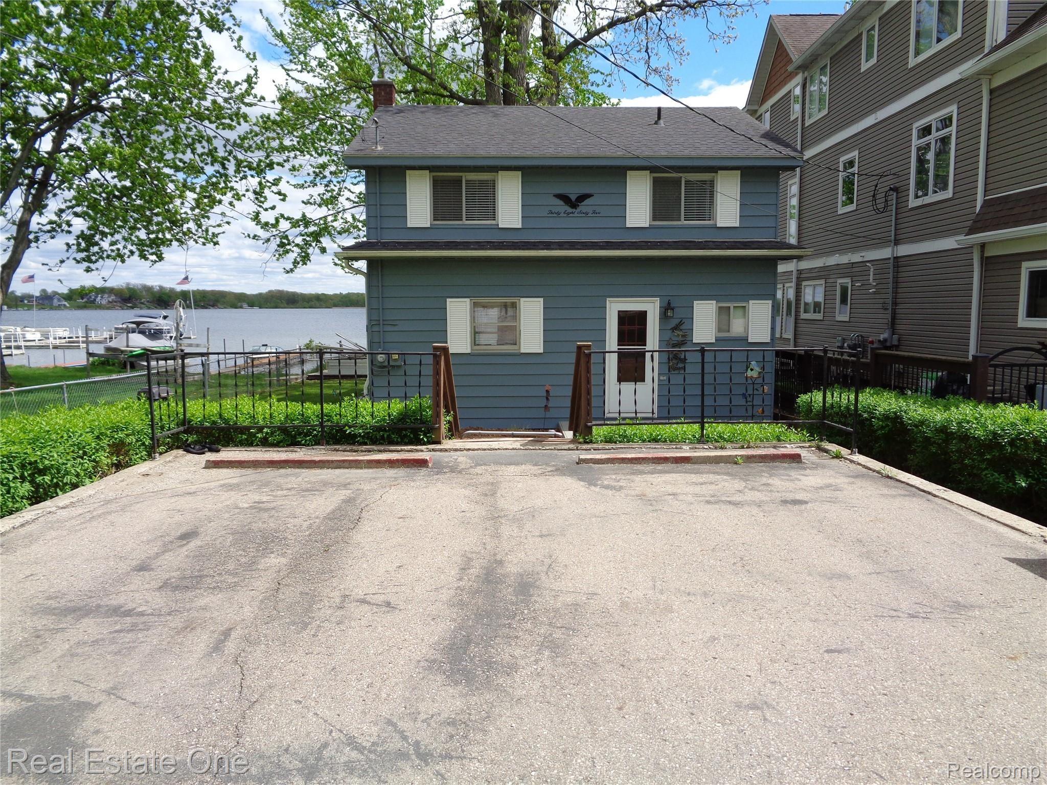 3865 Hunt Road Lapeer, MI 48446 - Photo 52 of 53 Property parking pad on street side. Note the large expensive homes being built on the lake... the green yard space to the left cannot be built on, it's part of the neighbor's lot, so you have that extra spacious feel.