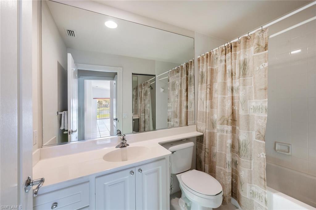 4231 Redonda Lane Naples, FL 34119 - Photo 15 of 28 a bathroom with a sink a toilet a mirror and shower curtain
