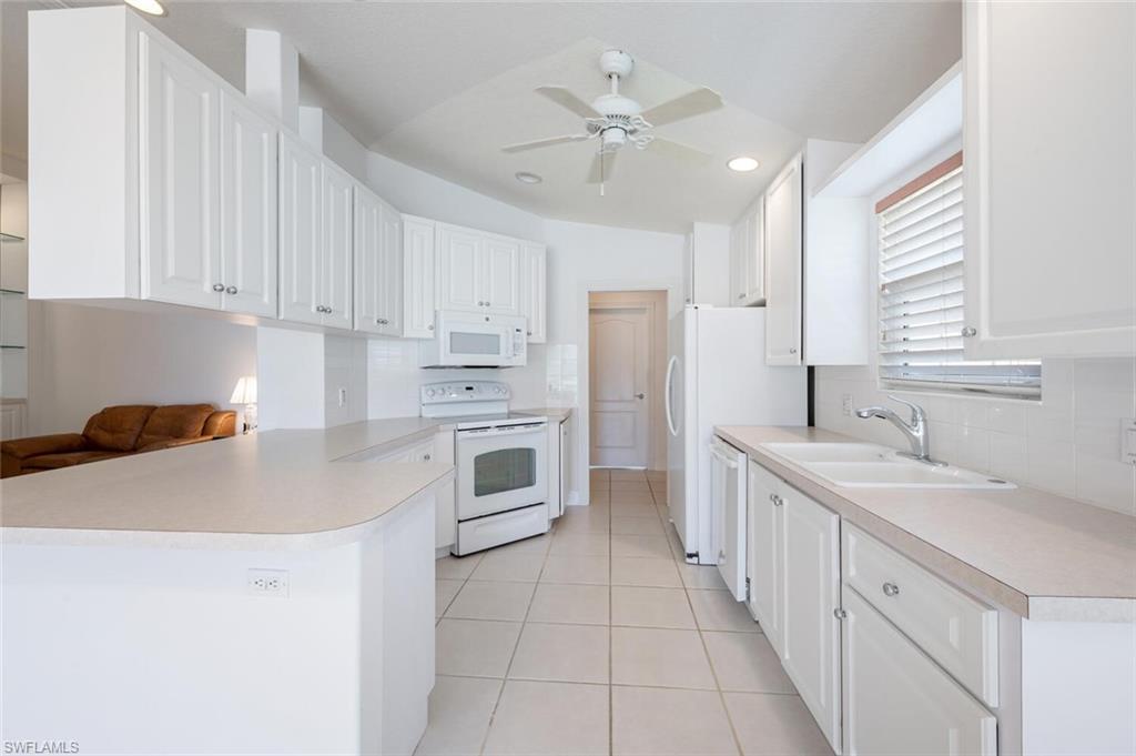 4231 Redonda Lane Naples, FL 34119 - Photo 7 of 28 a kitchen with a sink a stove a refrigerator and white cabinets
