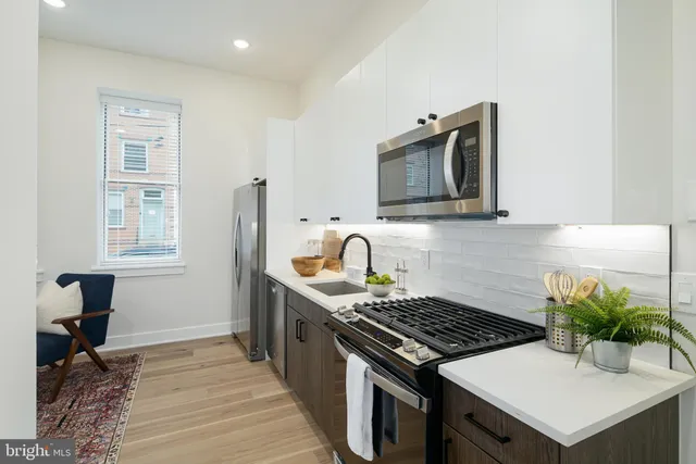 a kitchen with stainless steel appliances a stove a sink cabinets and a wooden floor