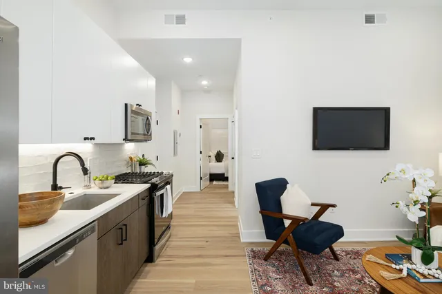 a kitchen with stainless steel appliances a stove a sink dishwasher and a microwave with wooden floor