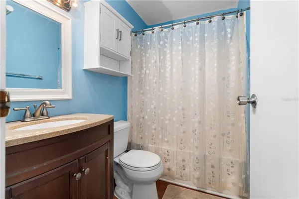 a bathroom with a granite countertop sink toilet and a mirror