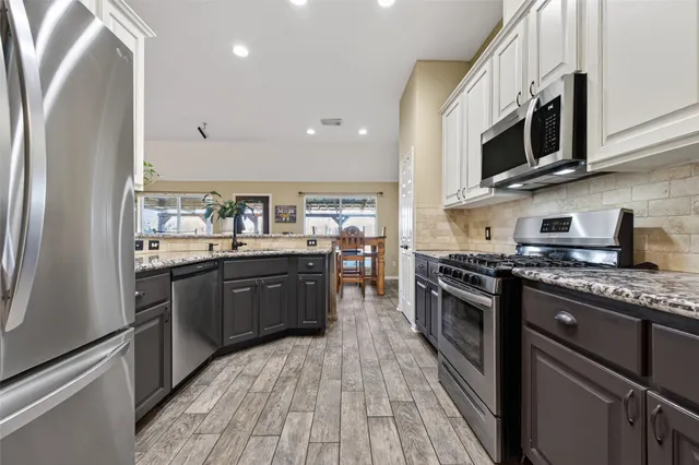 a kitchen with stainless steel appliances granite countertop a stove a sink and a refrigerator