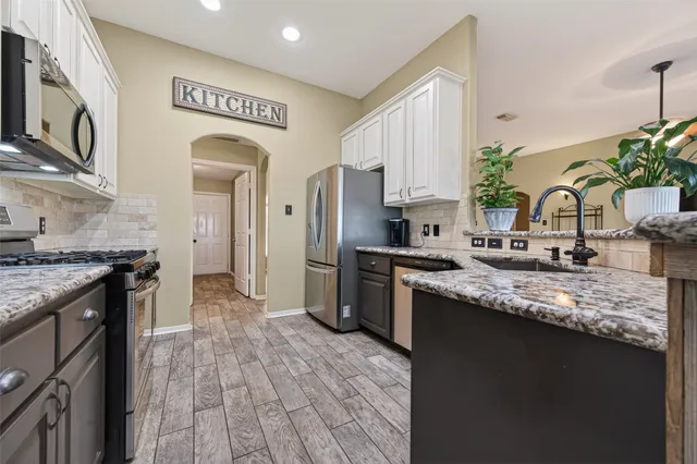 a kitchen with stainless steel appliances granite countertop a sink stove and refrigerator