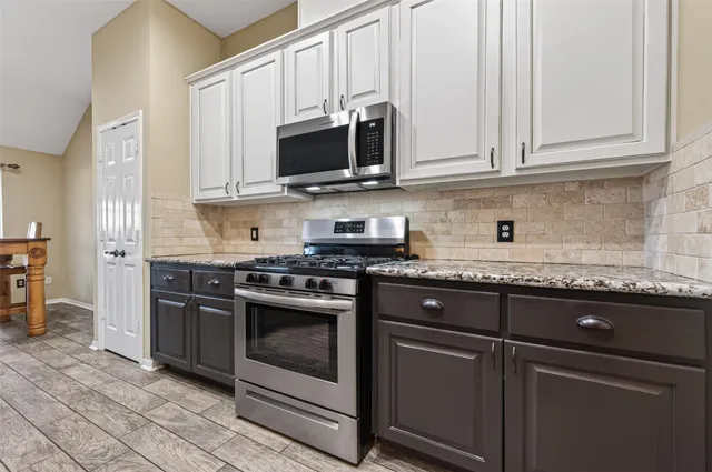 a kitchen with stainless steel appliances granite countertop a stove microwave and cabinets