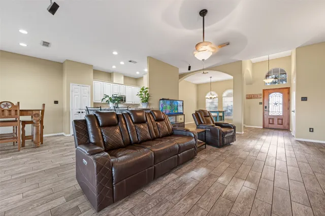 a living room with furniture a dining table wooden floor and a chandelier