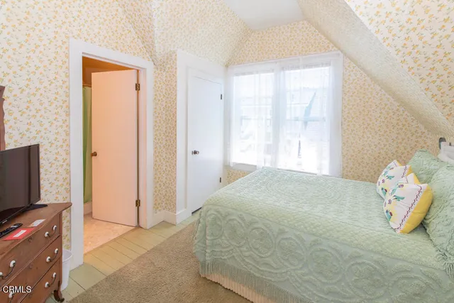 a bedroom with a bed a mirror on dresser and a window