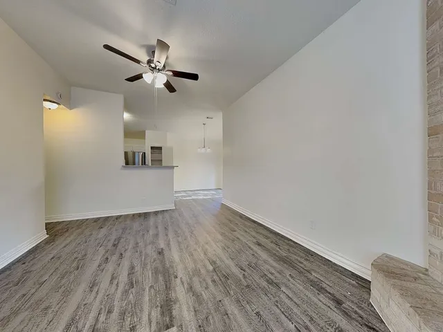 a view of empty room with wooden floor and ceiling fan