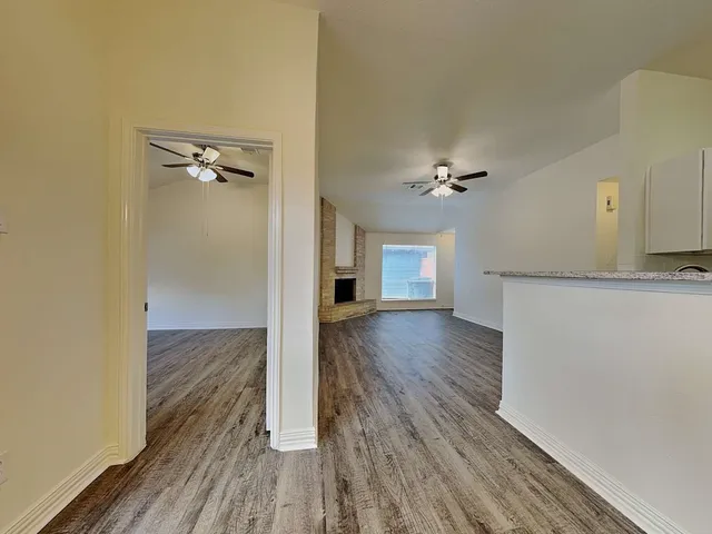 a view of a room with wooden floor and a ceiling fan