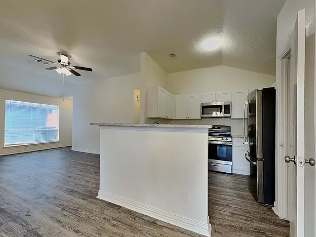a view of kitchen with stainless steel appliances refrigerator stove microwave and cabinets