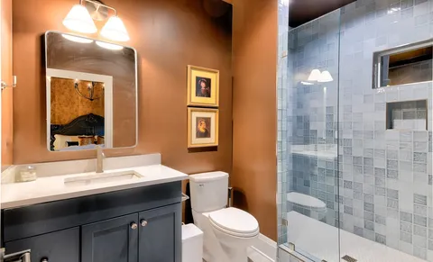 a bathroom with a sink a toilet a mirror and shower