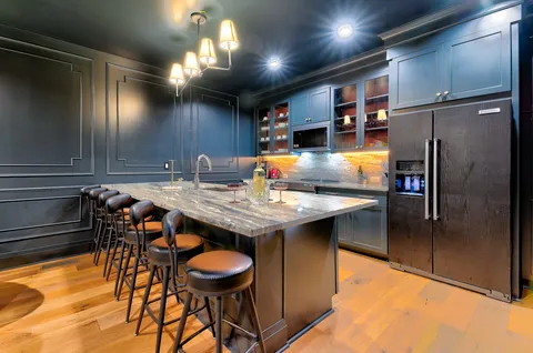 a kitchen with stainless steel appliances kitchen island granite countertop a table chairs in it and wooden floors