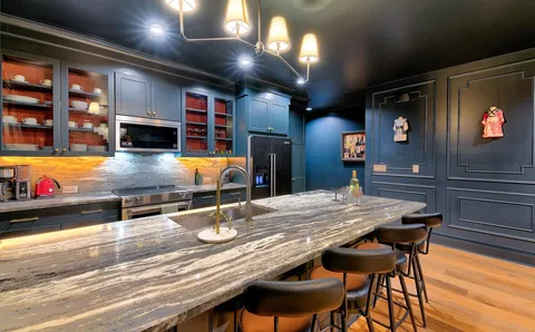 a kitchen with stainless steel appliances kitchen island granite countertop a table chairs and a refrigerator