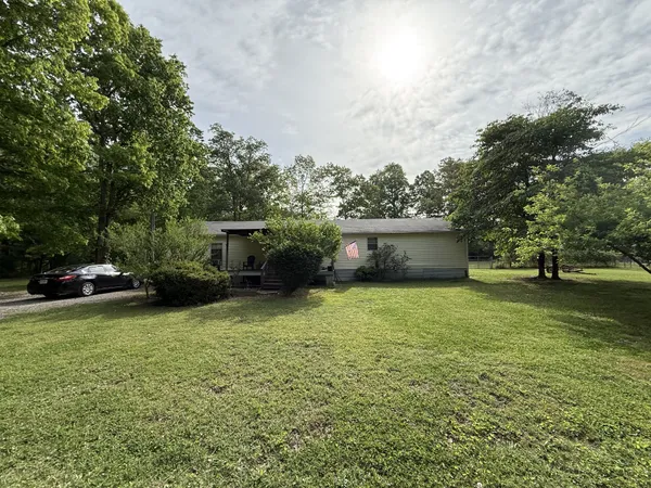 a front view of a house with a garden and trees