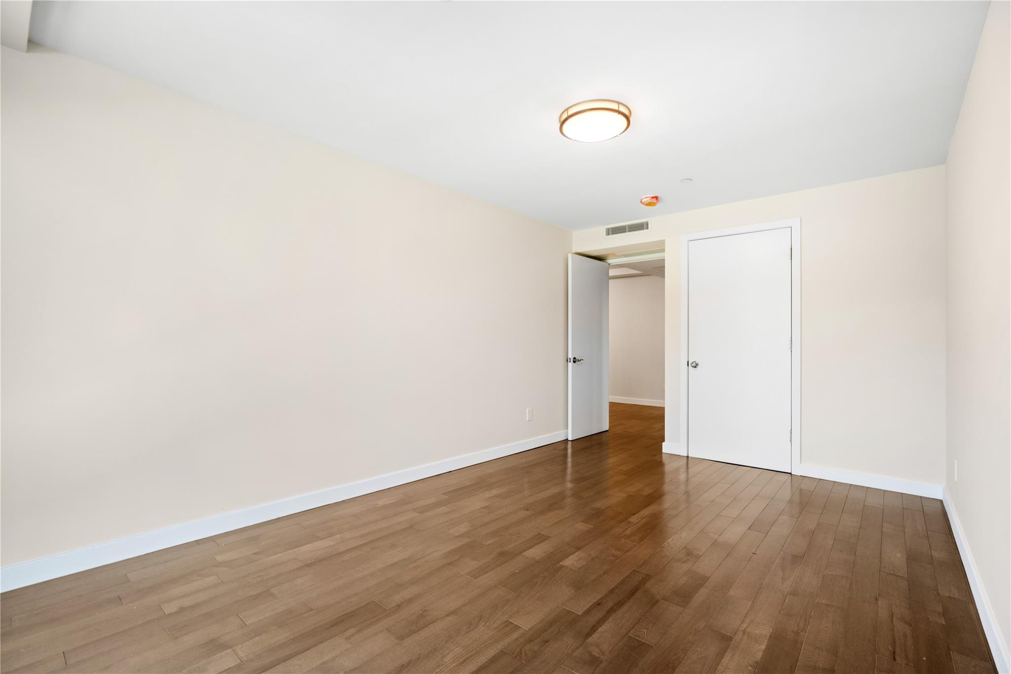 9745 63rd Drive, Unit 7A Queens, NY 11374 - Photo 15 of 20 a view of an empty room with wooden floor