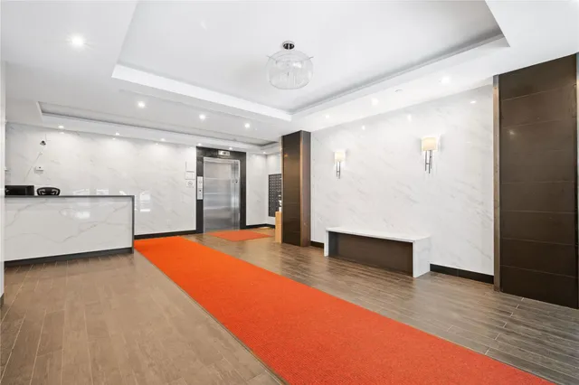 a view of an empty room with wooden floor and a kitchen