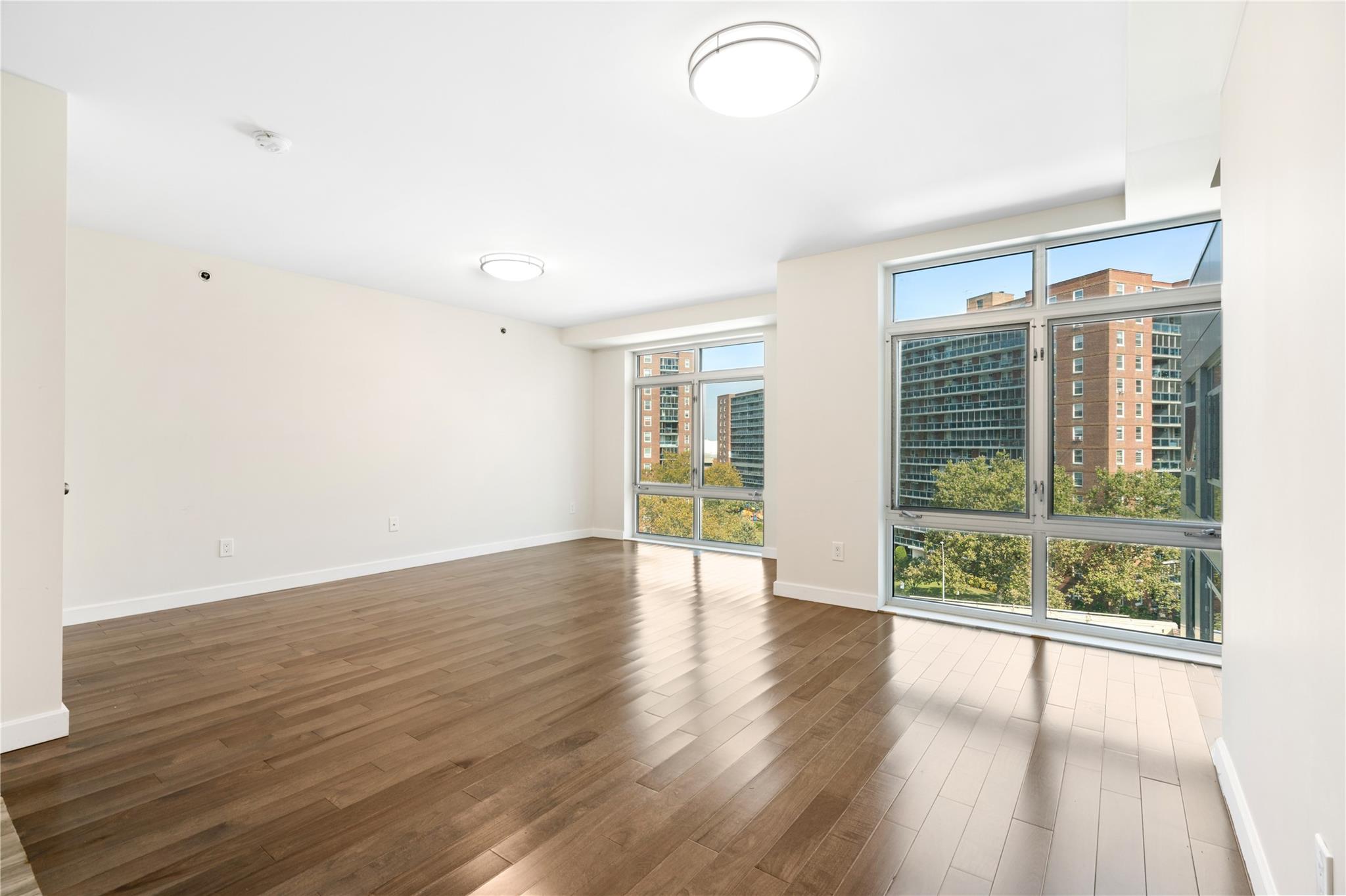 9745 63rd Drive, Unit 7A Queens, NY 11374 - Photo 3 of 20 a view of an empty room with wooden floor and a window