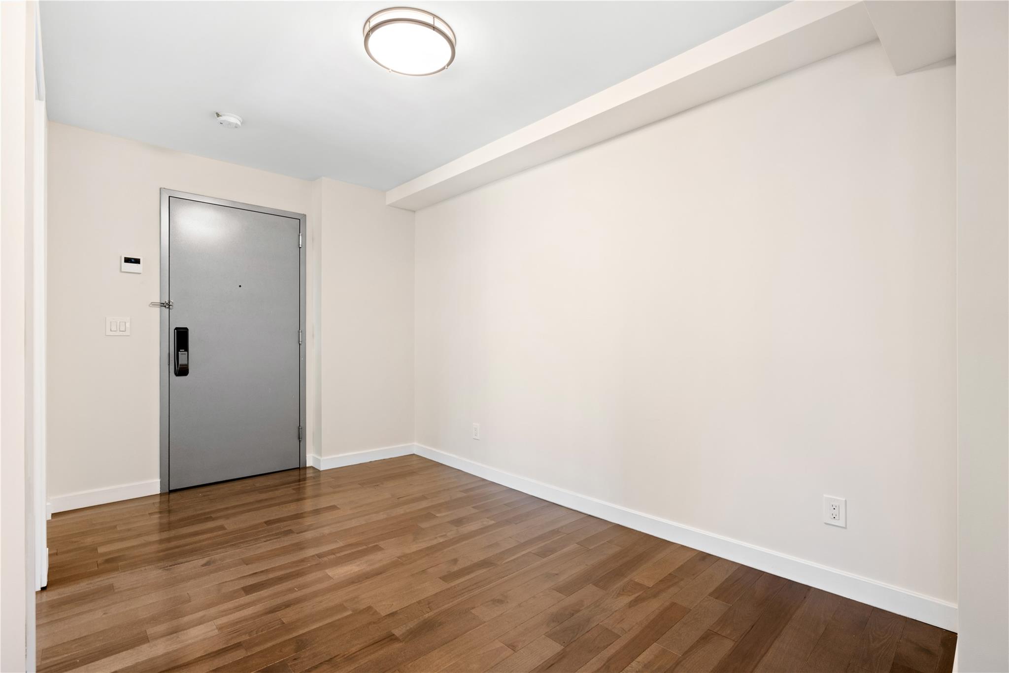9745 63rd Drive, Unit 7A Queens, NY 11374 - Photo 10 of 20 an empty room with wooden floor and windows