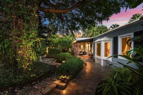 a backyard of a house with table and chairs under an umbrella