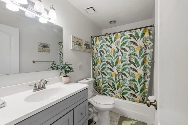 a bathroom with a granite countertop sink a toilet and a mirror