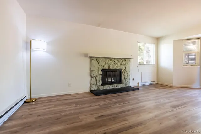 an empty room with wooden floor a fireplace and windows