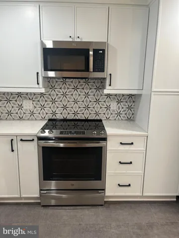 a kitchen with granite countertop white cabinets and stainless steel appliances
