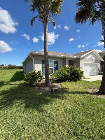 a view of a house with a yard and potted plants