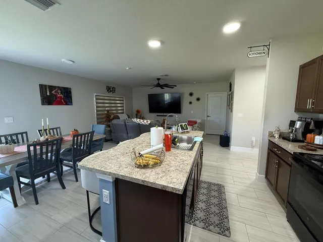 a living room with stainless steel appliances furniture a rug and a kitchen view