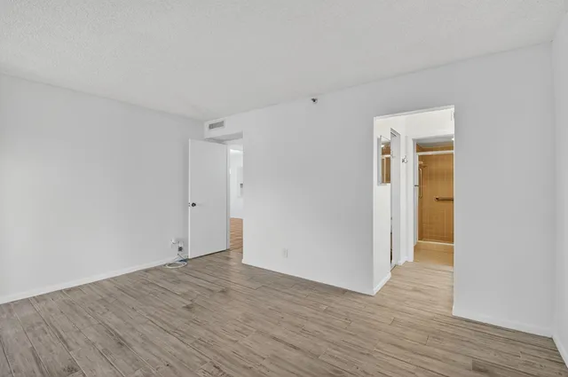 a view of an empty room with wooden floor and closet