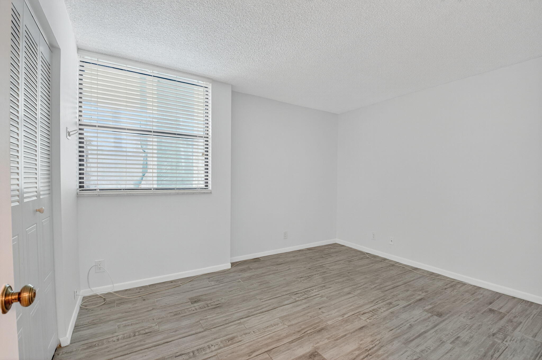 1850 Homewood Boulevard, Unit 214 Delray Beach, FL 33445 - Photo 16 of 38 a view of an empty room with wooden floor and a window